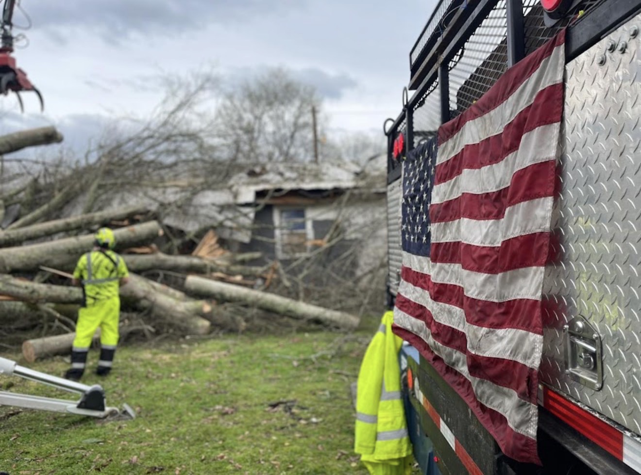 Crew member and American flag on a grapple truck during tornado cleanup