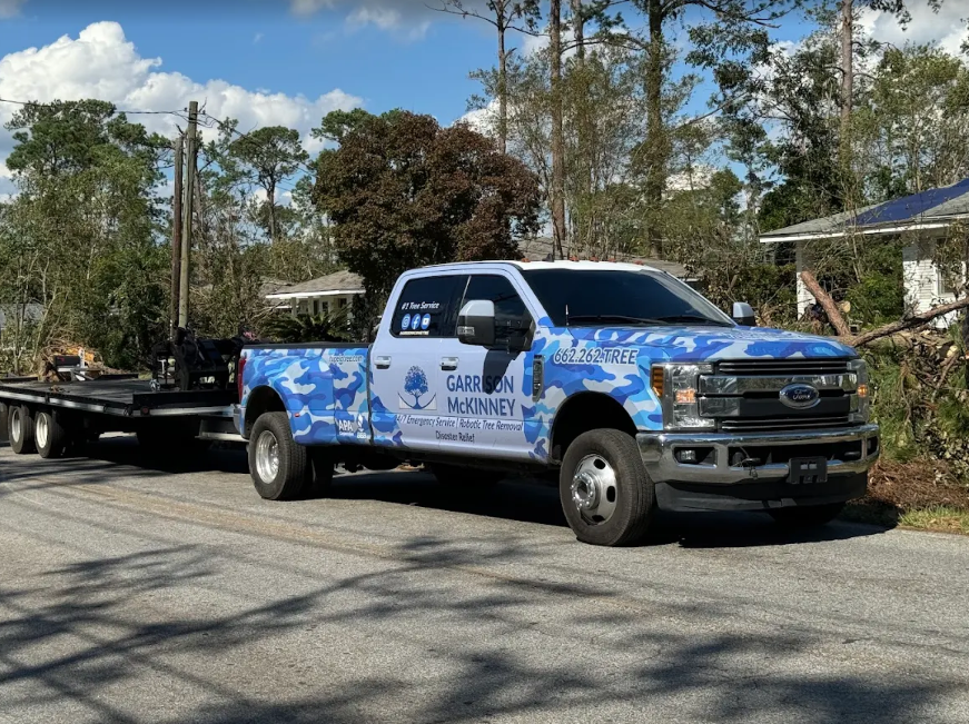 Garrison McKinney camo crew truck and trailer staged on a storm damaged street