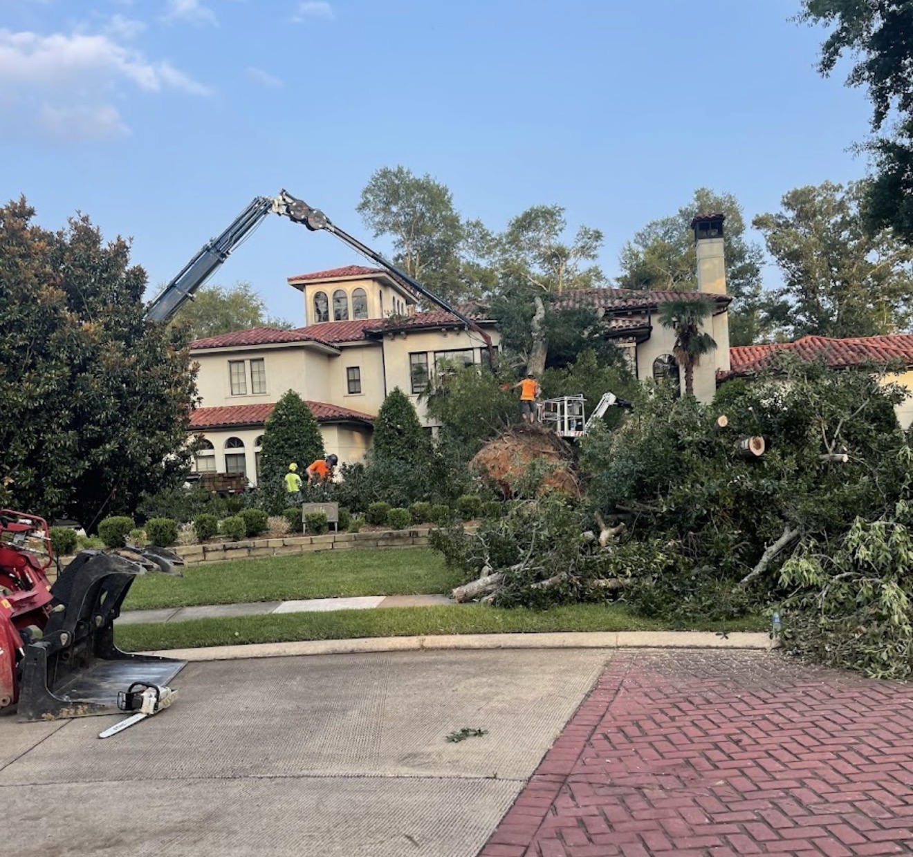 Crane crew removing a fallen oak off a large home after a storm